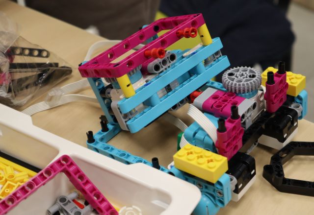 Na zdjęciu znajduje się niedokończony robo-samochód z LEGO oraz pudełko z innymi elemenatmi.