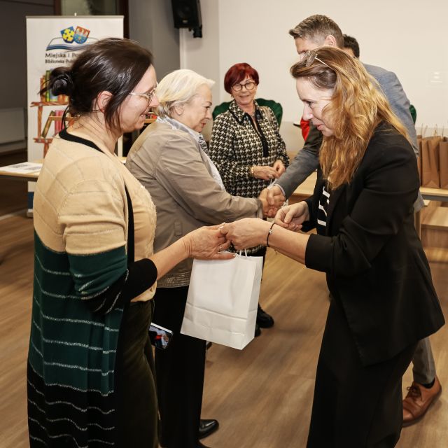 Na zdjęciu znajdują się trzy kobiety, a na przeciwko nich stoją osoby wręczające im upominki.