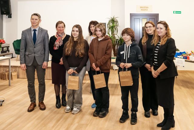 Na zdjęciu znajduje się trójka uczniów z upominkami, wraz z nimi do zdjęcia stoją cztery kobiety oraz jeden mężczyzna. 