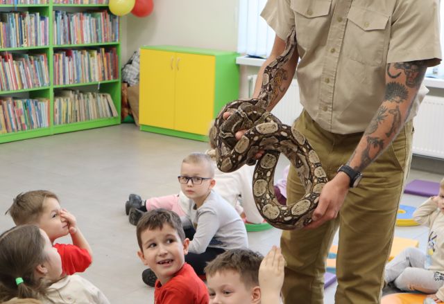 mężczyzna podróżnik pokazuje dizeciom węża