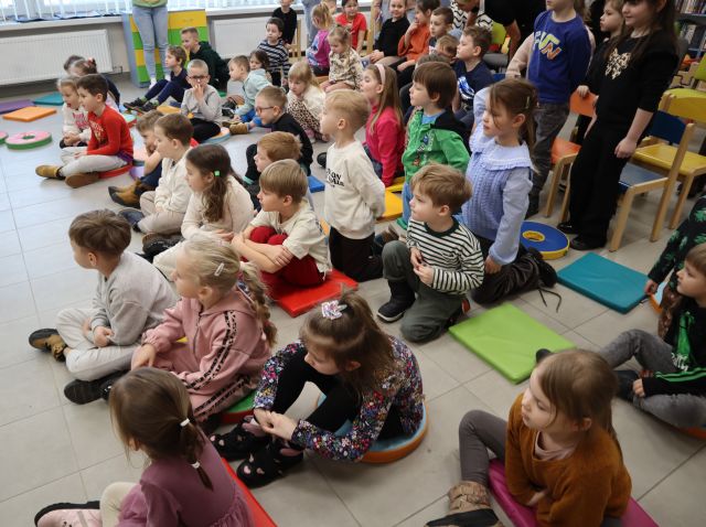 na zdjęciu przedszkolaki siedzące na podłodze i krzesełkach