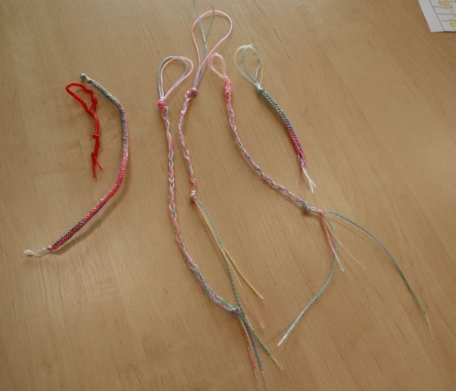 Na zdjęciu znajduje się pięć kolorowych breloczków wykonanych z żyłki, breloczki leżą na stole.