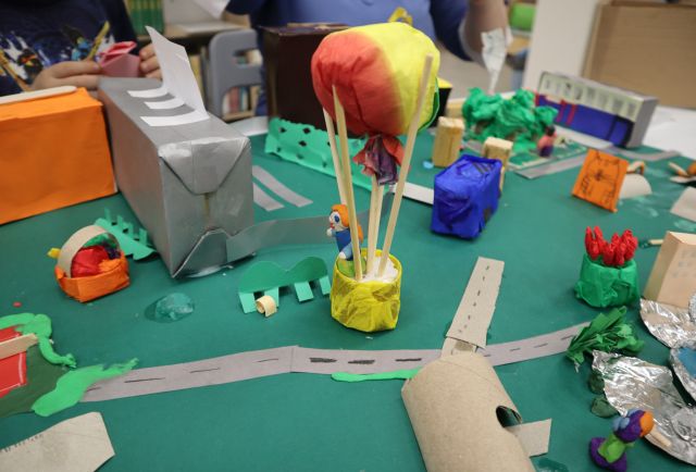 Na zdjęciu znajduje się makieta, na której stoi balon, dookoła niego znajdują się budynki, drogi oraz roślinność.