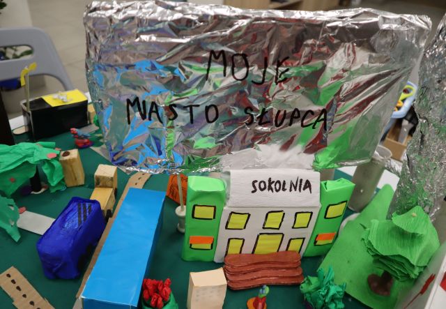 Na zdjęciu znajduje się kawałek makiety przedstawiający kino Sokolnia oraz inne budynki i drogi, za kinem znajduje się duży napis na sreberku Moje Miasto Słupca.