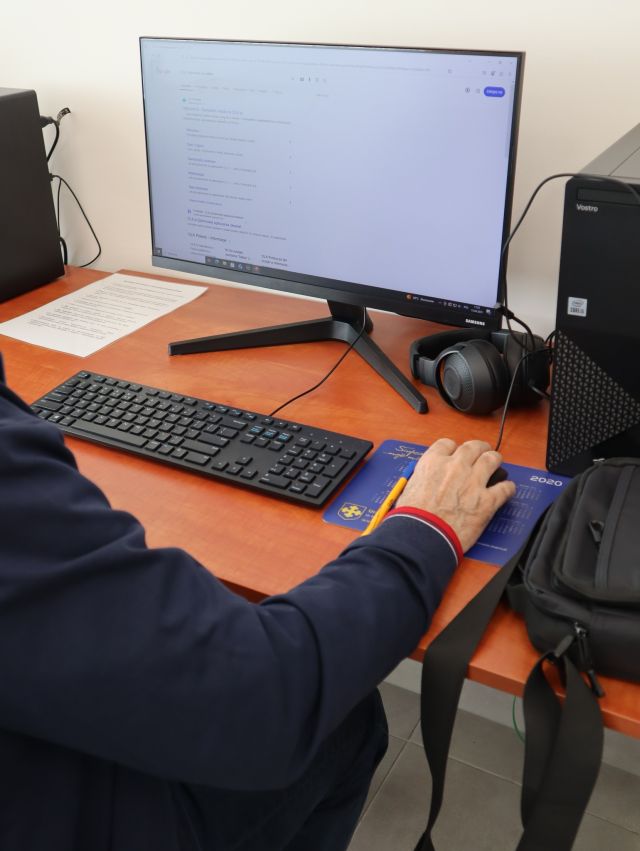 Na zdjęciu znajduje się komputer przy którym ktoś siedzi.