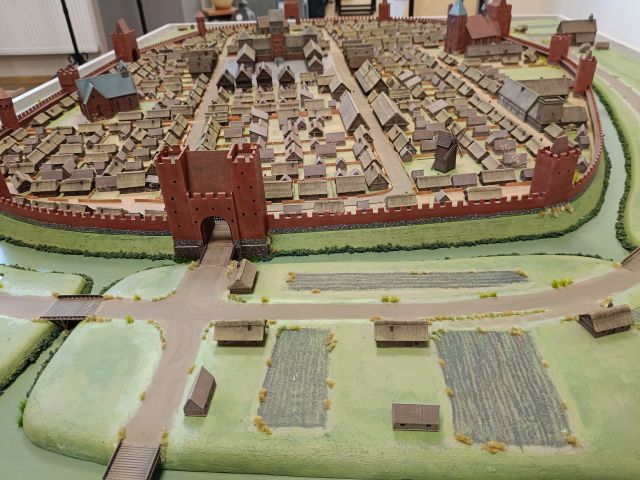 Na zdjęciu znajduje się fragment makiety miasta Słupca przedstawiający pola i wejście do ogrodzonego miasta.