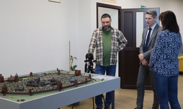 Na zdjęciu znajduje się dwóch mężczyzn oraz kobieta stoją oni przy makiecie miasta, która znajduje się na holu Biblioteki.