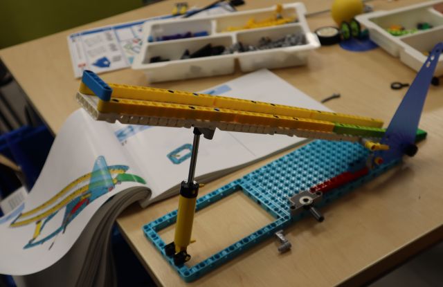 Na zdjęciu znajduje sie zbudowana z klocków LEGO skocznia leżąca na stole, a obok niej klocki LEGO i instrukcja.