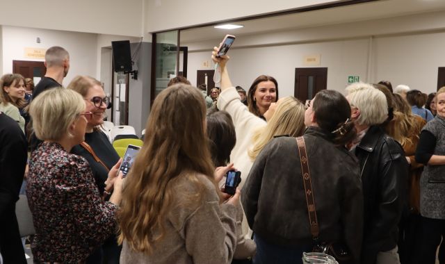 Na zdjęciu znajdują się ludzie stojący dookoła robiących sobie zdjęć kobiet.
