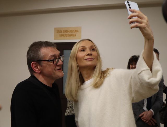 Na zdjęciu znajduje się mężczyzna oraz kobieta z wyciągniętą ręką i robi zdjęcie.