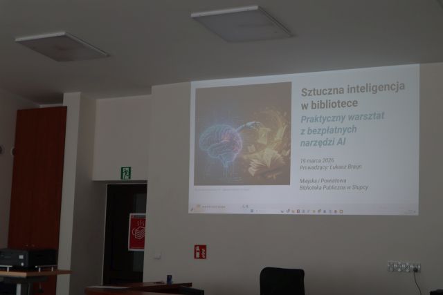 Na zdjęciu znajduje się wyświetlana na ścianie prezentacja dotyczącą sztucznej inteligencji.