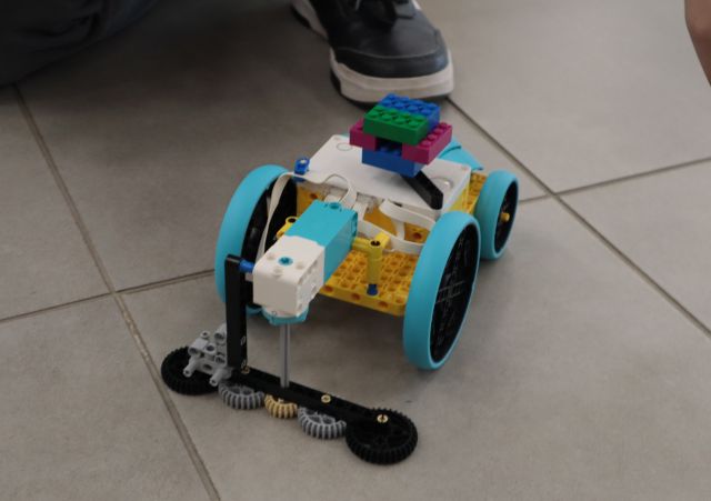 Na zdjęciu znajduje się zbudowany z klocków LEGO samochód myjący podłogę. Auto leży na kafelkach.