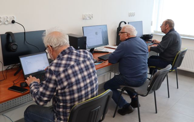Na zdjęciu znjduje się trzech mężczyzn, przy komputerach. Warsztaty odbywają się w sali komputerowej.