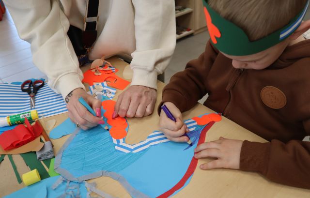 Na zdjęciu znajduje się chłopiec, który wraz z mamą maluje przy stole niebieskie skrzydła.