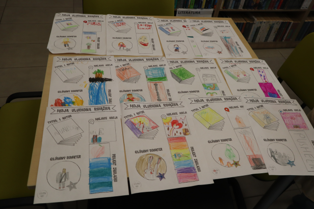 Na zdjęciu znajduje się stolik pełen kolorowych kart pracy przedstawiających zakładkę do książki, okładkę ulubionej książki, bohatera oraz miejsce akcji.