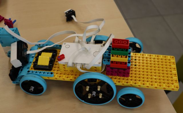 Na zdjęciu znajduje się zbudowany z klocków LEGO samochód, który leży na drewnianym stoliku.