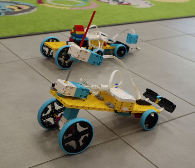 Na zdjęciu znajdują się dwa roboty, samochody zbudowane z klocków LEGO i się ścigają.