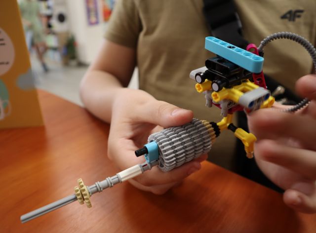 Na zdjęciu znajduje się konstrukcja zbudowana z klocków LEGO, którą chłopiec trzyma w ręce.