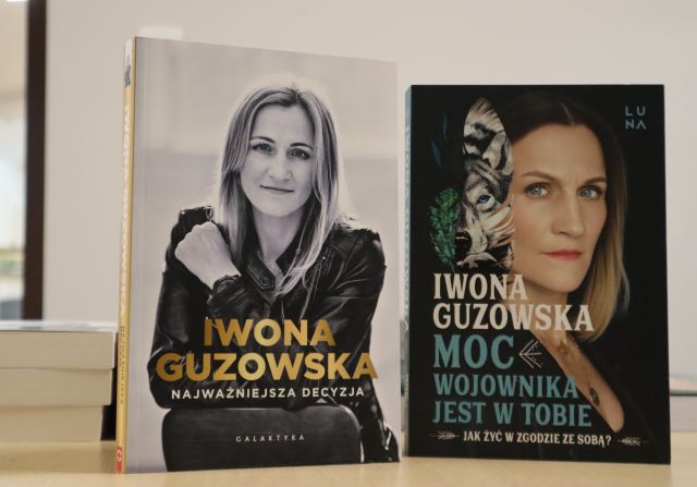 Na zdjęciu znajdują się książki na stoliku, dwie są ustawione okładkami obie przedstawiają kobietę i są autorstwa Iwony Guzowskiej, książka po prawej, ze złotym napisem to najważniejsza decyzja, a książka po lewej to moc wojownika jest w tobie.
