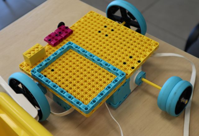 Na zdjęciu znajduje się stojąca na stoliku konstrukcja z klocków LEGO przedstawiająca plaże na kółkach.