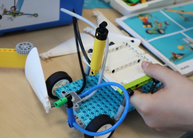 Na zdjęciu znajduje się zbudowana z klocków LEGO konstrukcja przypominająca łódkę, dookoła na stole leżą klocki oraz instrukcja.