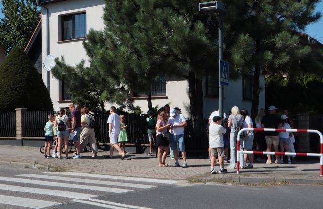 Na zdjęciu znajdują się uczestnicy gry wawrzynkowej na chdoniku przy ulicy, w tle znajduje się dom mieszkalny.