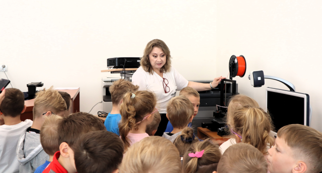 na zdjęciu bibliotekarka pokazująca przedszkolakom drukarkę 3d