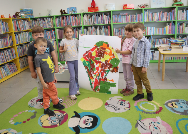 na zdjęciu 5 przedszkolaków prezentująca swoje wyklejone drzewo na dużym arkuszu papieru