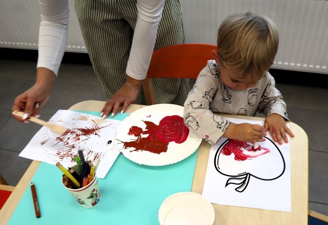 na zdjęciu mały chłopiec malujący jabłko na papierze, obok dłonie dorosłej kobiety