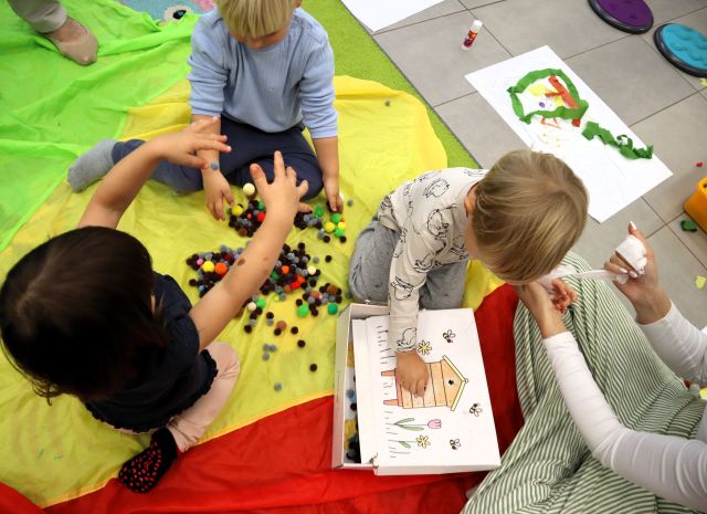 na zdjęciu 3 małych dzieci bawi się kolorowymi piłeczkami
