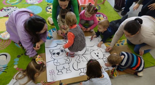 małę dzieci i rodzice zamalowują koty na dużej białe kartce
