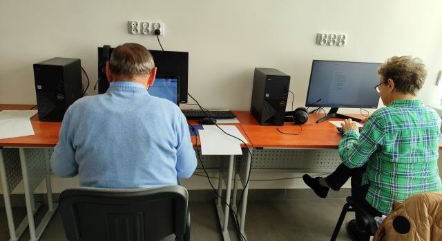 mężczyzna i kobieta siedzą przy komputerach