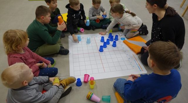 dzieci układają kolorowe plastikowe kubeczki na macie