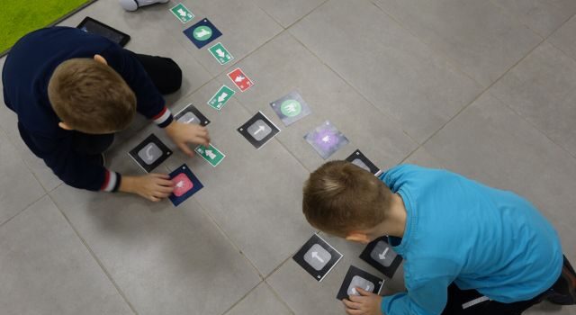 dwóch chłopców steruje przy pomocy tabletów robotami Photon