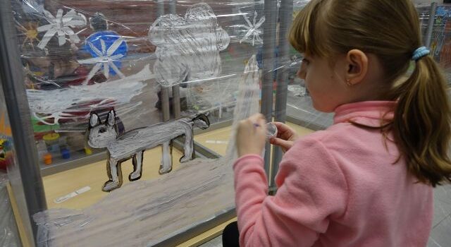 dziewczynka maluje psa na folii przymocowanej do stołów