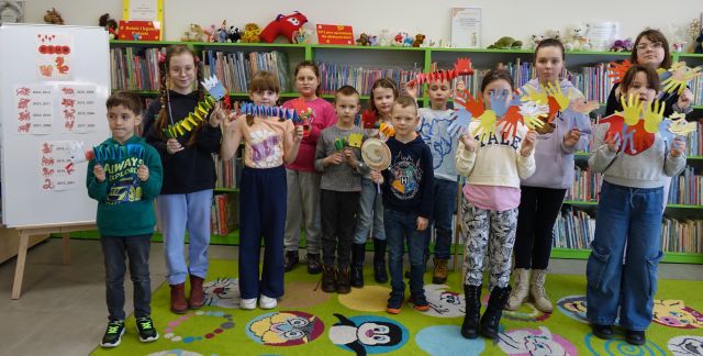 dzieci pozują do zdjęcia z wykonanymi przez siebie kolorowymi smokami z papieru