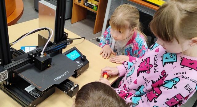 4 dzieci patrzy na drukarkę 3d