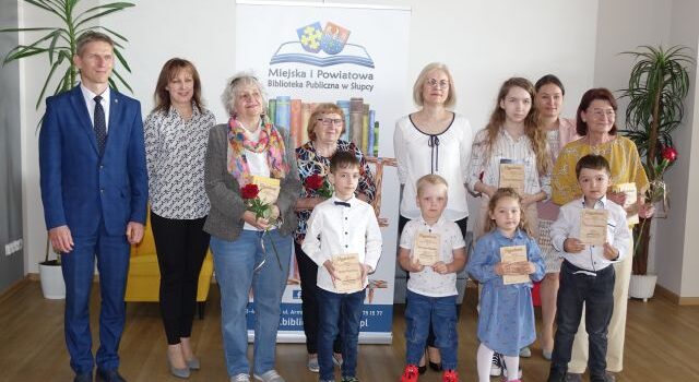 najaktywniejsi czytelnicy roku 2023 z burmistrzem i bibliotekarkami pozują do zdjęcia z dyplomami i czerwonymi różami