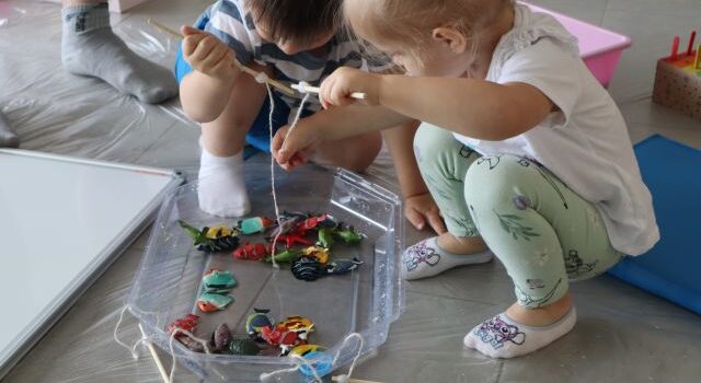 małe dzieci wyławiają zabawkowe rybki z miski