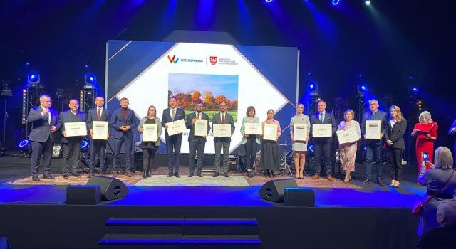 na zdjęciu osobyodbierające nagrody, w tle zdjęcie z logo konkursu