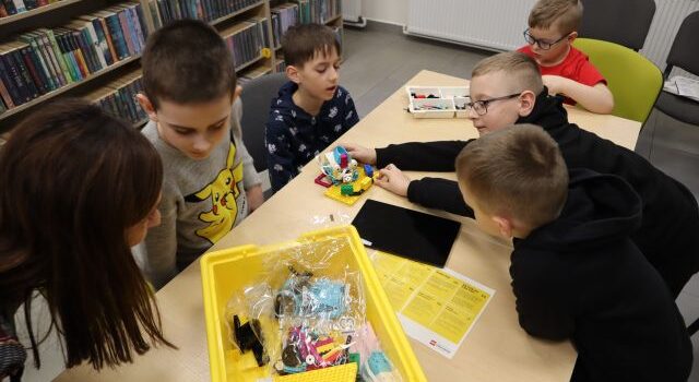 5 chłopców składa klocki Lego używając tableta i kabelków