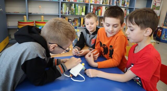 4 chłopców buduje robota z klocków Lego