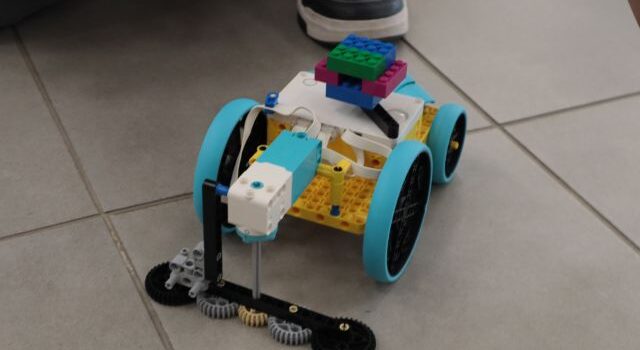 Na zdjęciu znajduje się zbudowany z klocków LEGO samochód myjący podłogę. Auto leży na kafelkach.